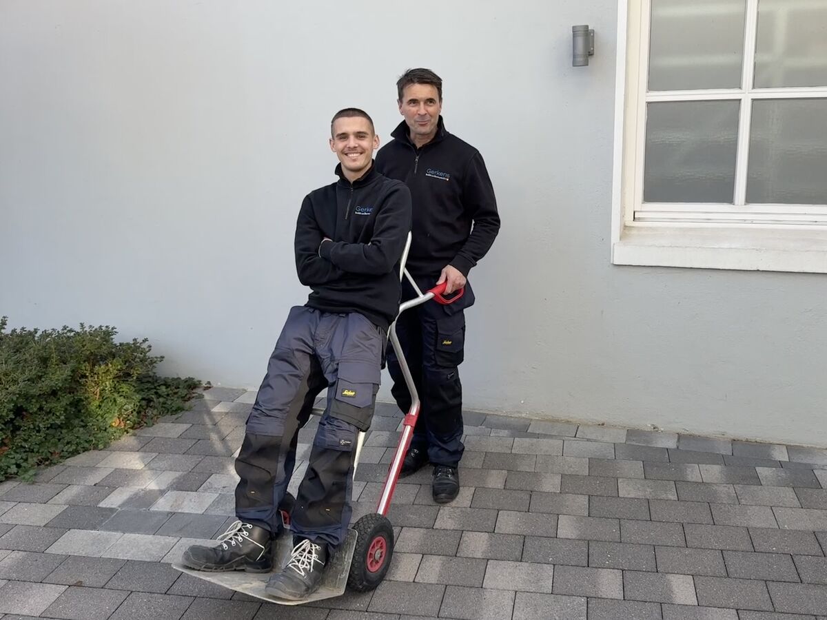 Zwei Kollegen bei der Arbeit vor einem Kundenhaus
